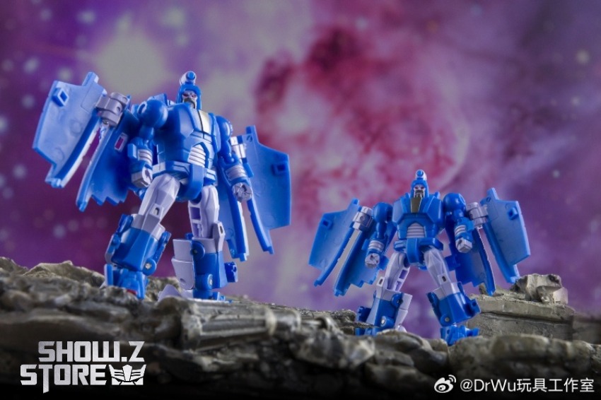 Blue and white transforming robot with red weapons on rocky terrain Blue and white transforming robot with red weapons on rocky terrain