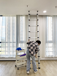 a girl is closing the en131 telescopic ladder indoor