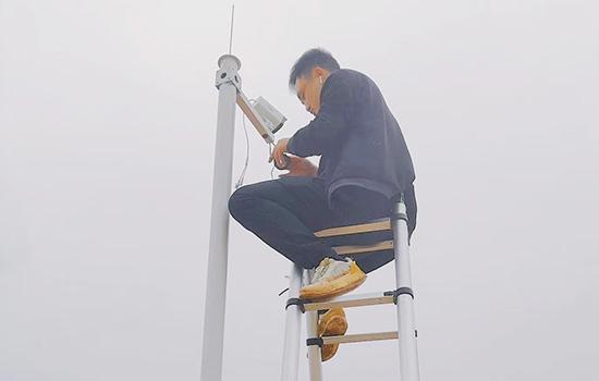 Un homme chevauchant une echelle telescopique double vérifiant une caméra