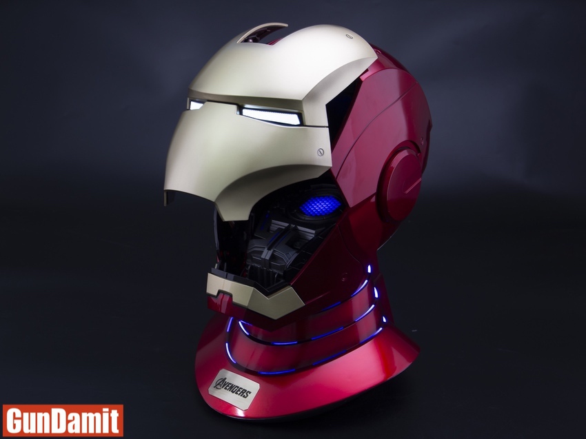 Side view of MST Iron Man helmet on LED-lit base showing half gold half red design with blue eye lights Side view of MST Iron Man helmet on LED-lit base showing half gold half red design with blue eye lights