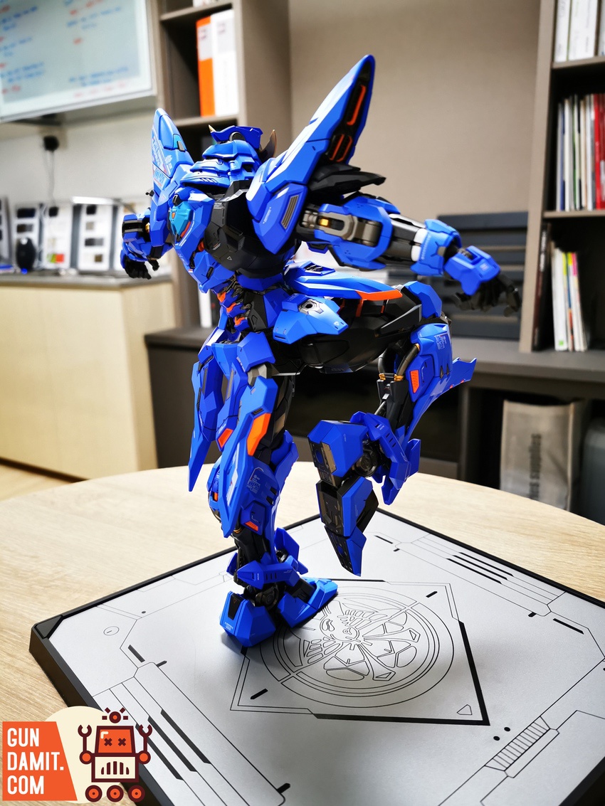 Rear angle view of MoShow MCT-J03 blue mecha showing wing thrusters and leg armor detail on display stand Rear angle view of MoShow MCT-J03 blue mecha showing wing thrusters and leg armor detail on display stand