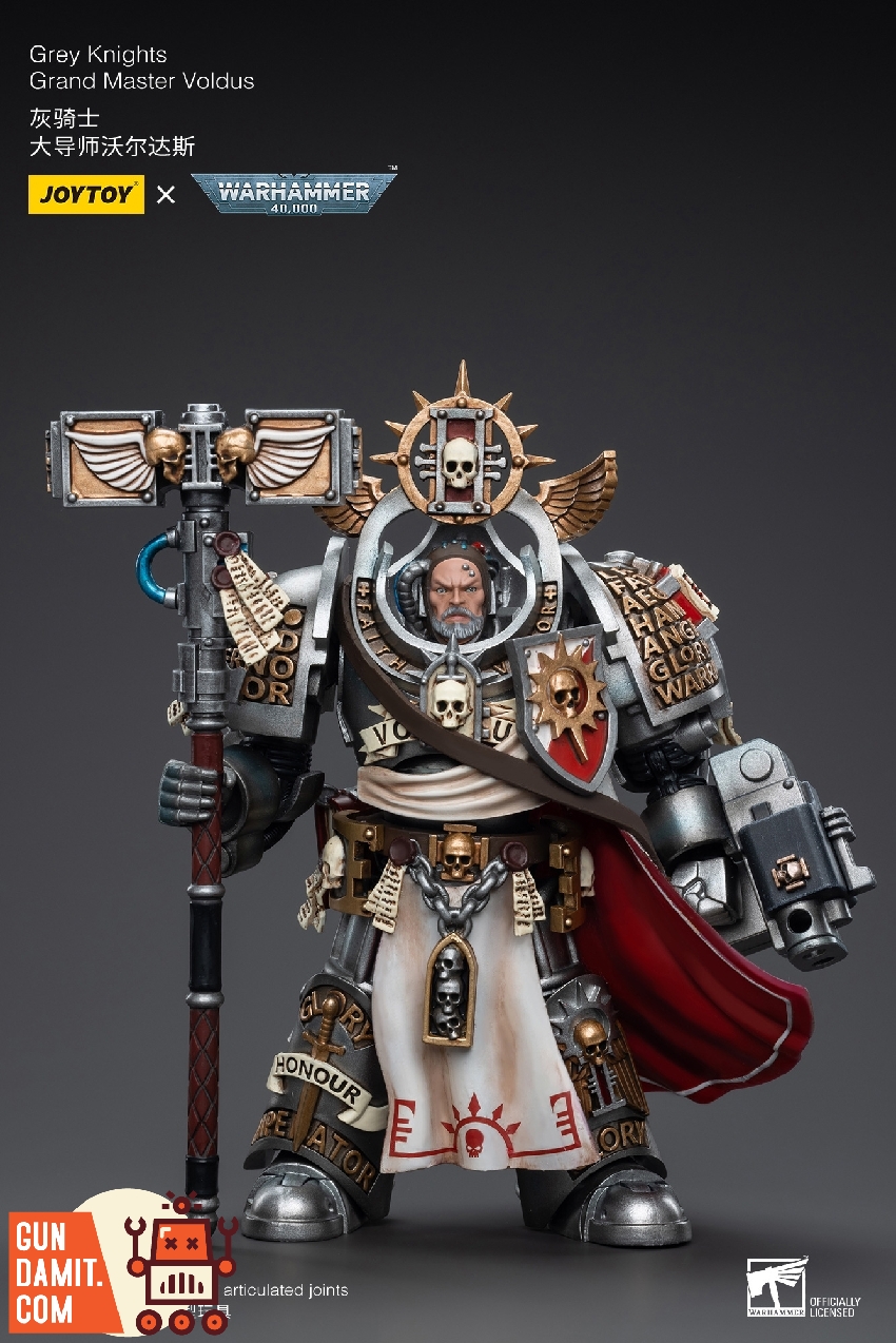 Front view of Voldus in ornate silver power armor with white tabard bearing red Inquisition symbols and raised Daemon Hammer Front view of Voldus in ornate silver power armor with white tabard bearing red Inquisition symbols and raised Daemon Hammer