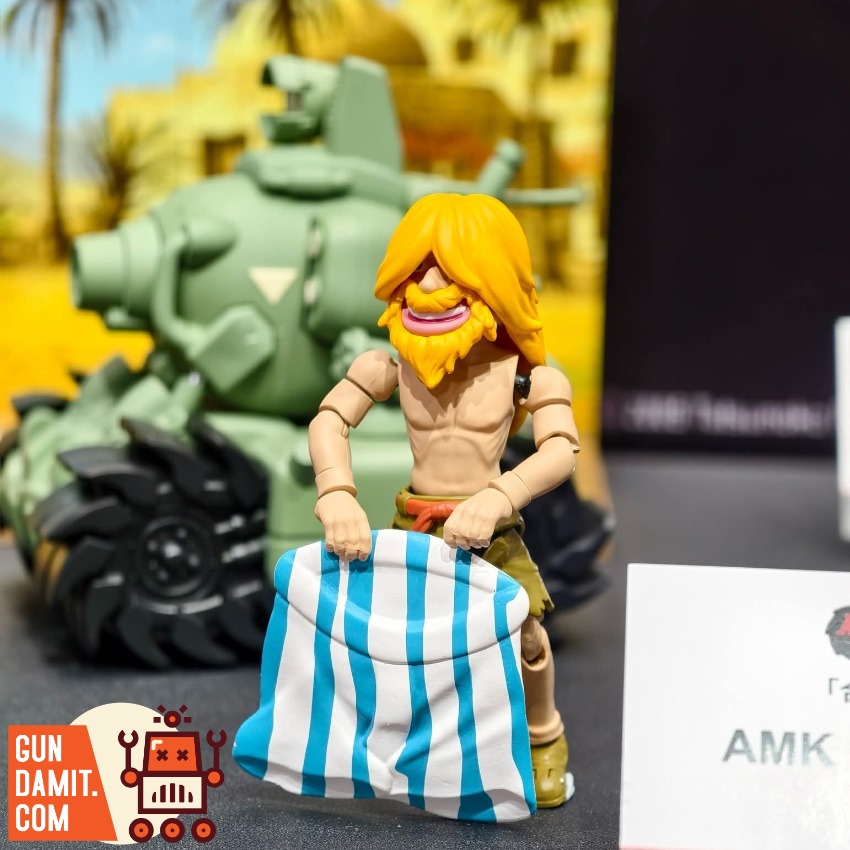 YoloPark AMK MINl Pro Series Metal Slug 3 Wave 1 Model Kit A toy figure with yellow hair holds a striped cloth in front of a YoloPark AMK MINl Pro Series Metal Slug 3 Wave 1 Model Kit A toy figure with yellow hair holds a striped cloth in front of a