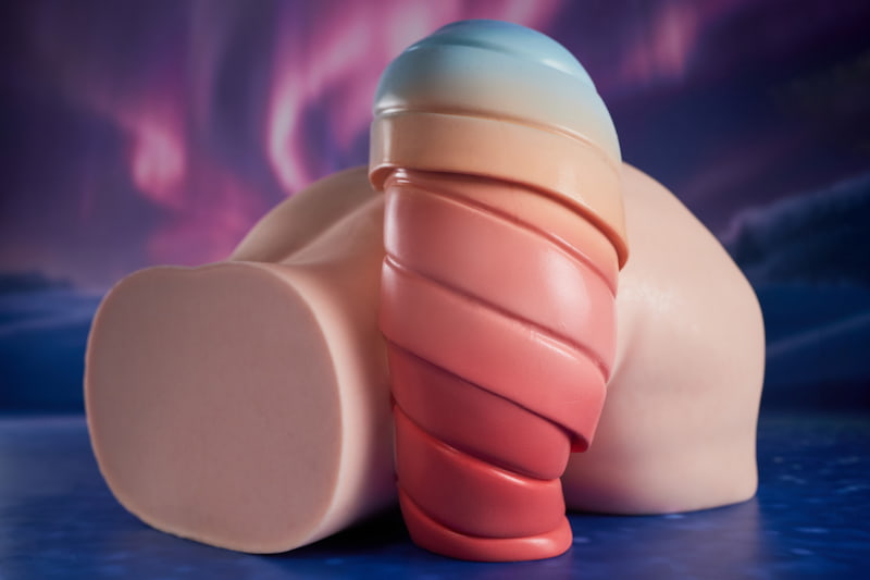 PA-Ray: This front-quarter hero shot focuses on the product's waist cross-section and side-hip profile laid flat, prominently showcasing the layered pink-to-blue gradient tail extending from the back against a dreamy aurora background.
