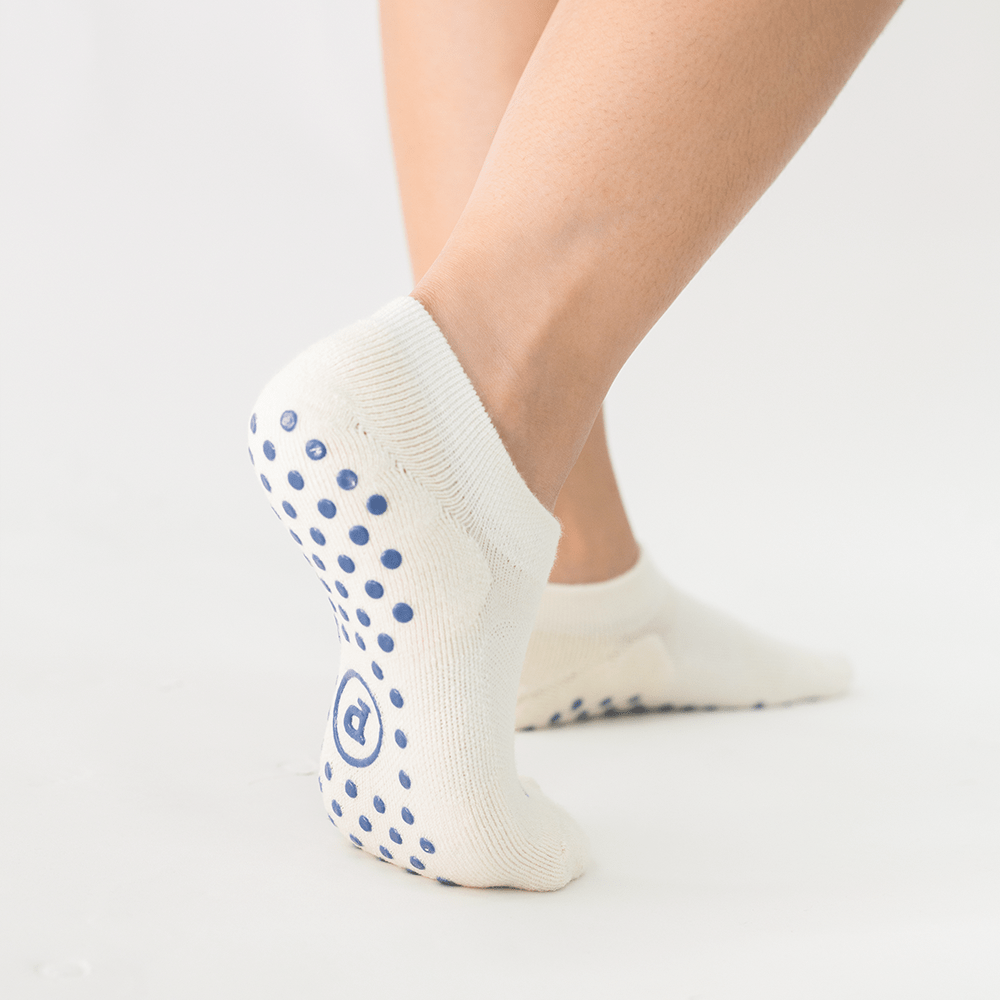 white ankle grip socks with circular silicone traction dots on the sole for indoor balance control