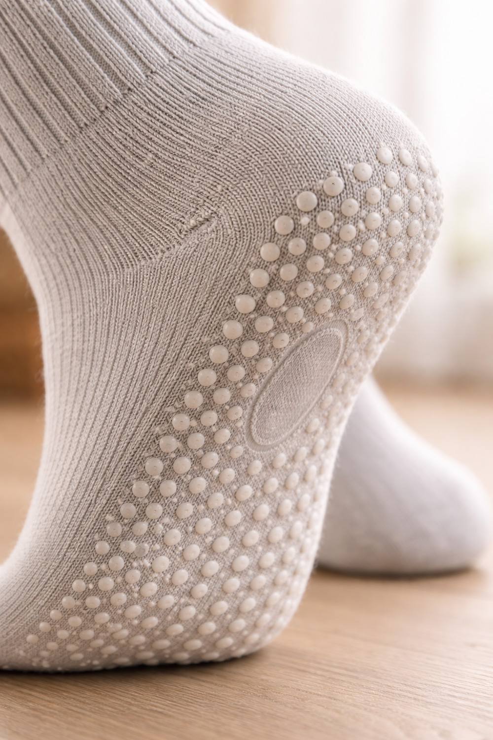Close-up of grip socks sole with silicone traction dots, illustrating anti-slip design that improves grip on smooth indoor floors.