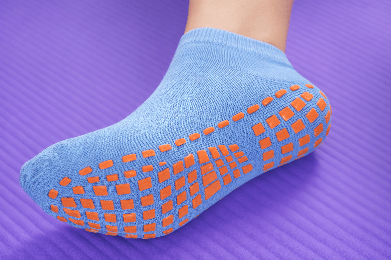 blue ankle grip socks with orange silicone pattern on yoga mat anti slip fitness socks close up