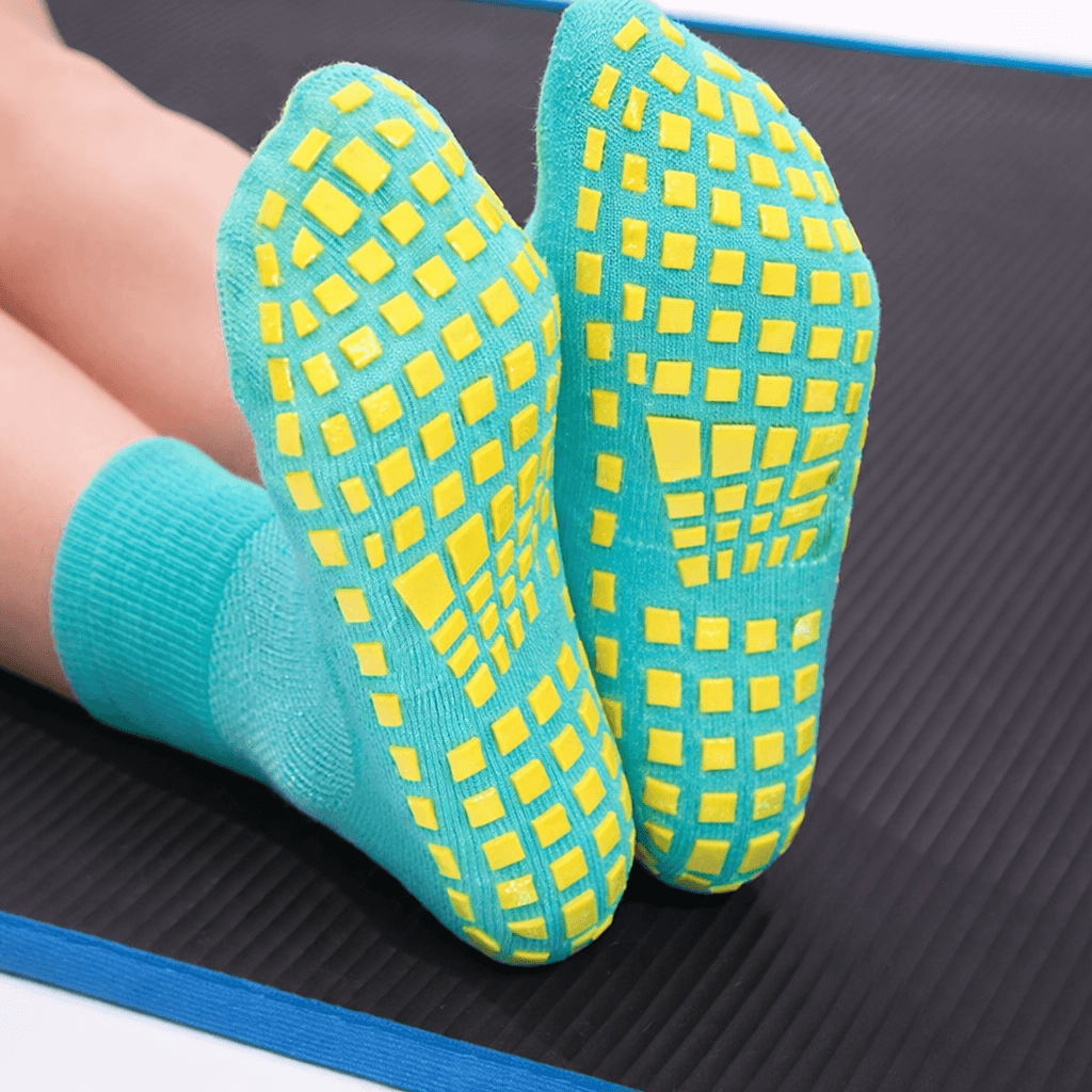 Turquoise grip socks with yellow square anti-slip pattern on sole, close-up on exercise mat, Trampoline training use
