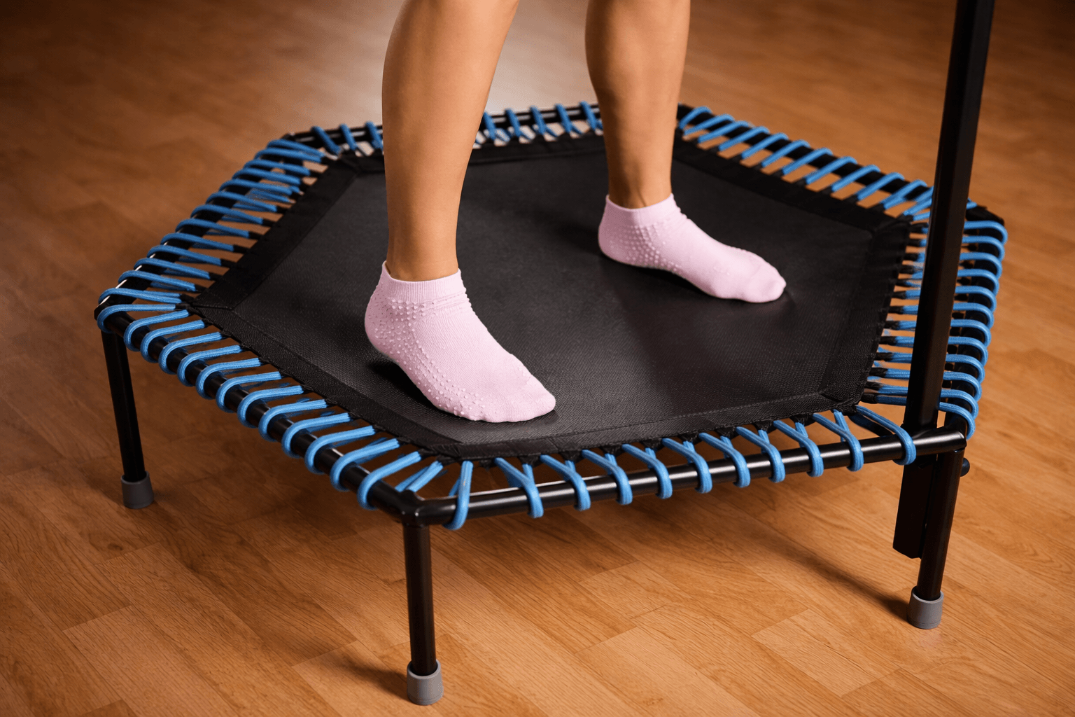Light pink grip socks with non-slip dots standing on mini Trampoline, indoor workout equipment close-up