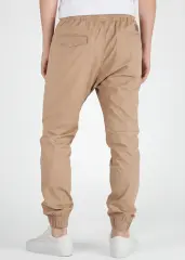 A rear view close-up of ItalyMorn men's khaki jogger pants on a model, highlighting the functional back pockets, clean fit, and durable fabric texture. Paired with white sneakers.