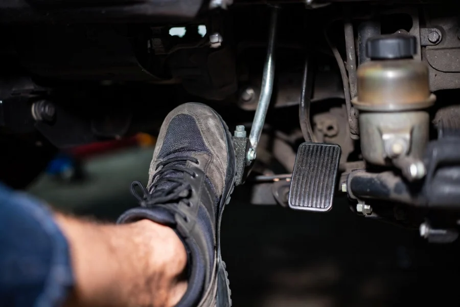 Mechanic checking a soft brake pedal, indicating potential issues with brake fluid or air in the brake lines.