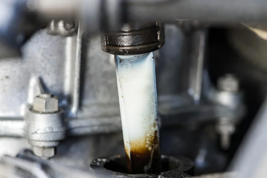 Engine oil dipstick showing milky oil indicating coolant contamination in the engine.