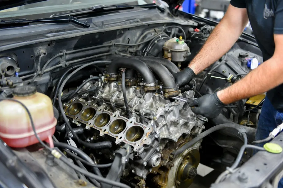 Mechanic replacing blown head gasket to fix milky oil contamination in engine.
