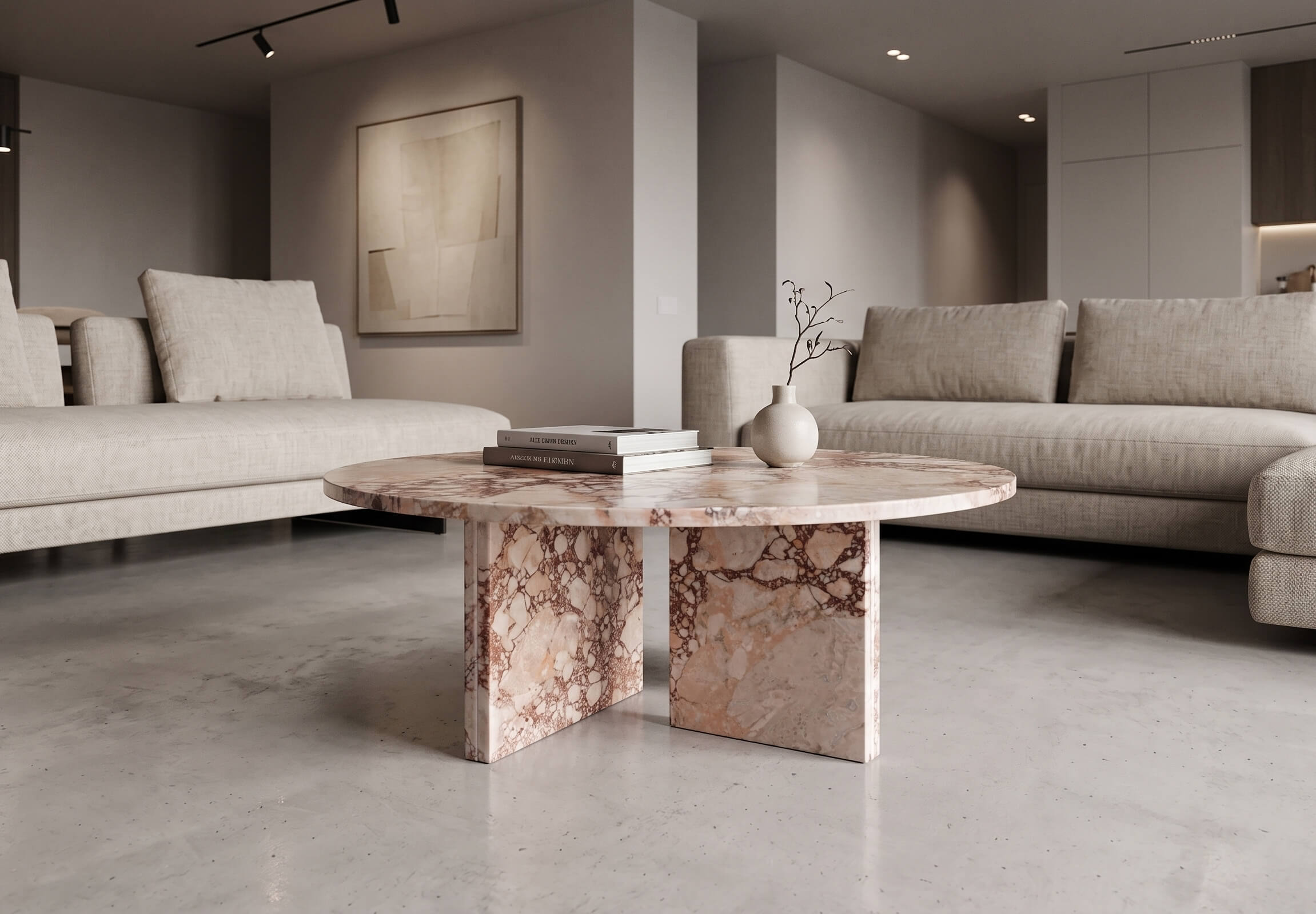 Diamond Pink marble round coffee table centered between two low-profile linen sectional sofas in a gallery-style minimalist living room — polished concrete floor reflecting table base, track lighting overhead, warm beige geometric abstract painting on mid-gray wall, matte white ceramic vase with dry branches and stacked hardcover books on marble surface.
