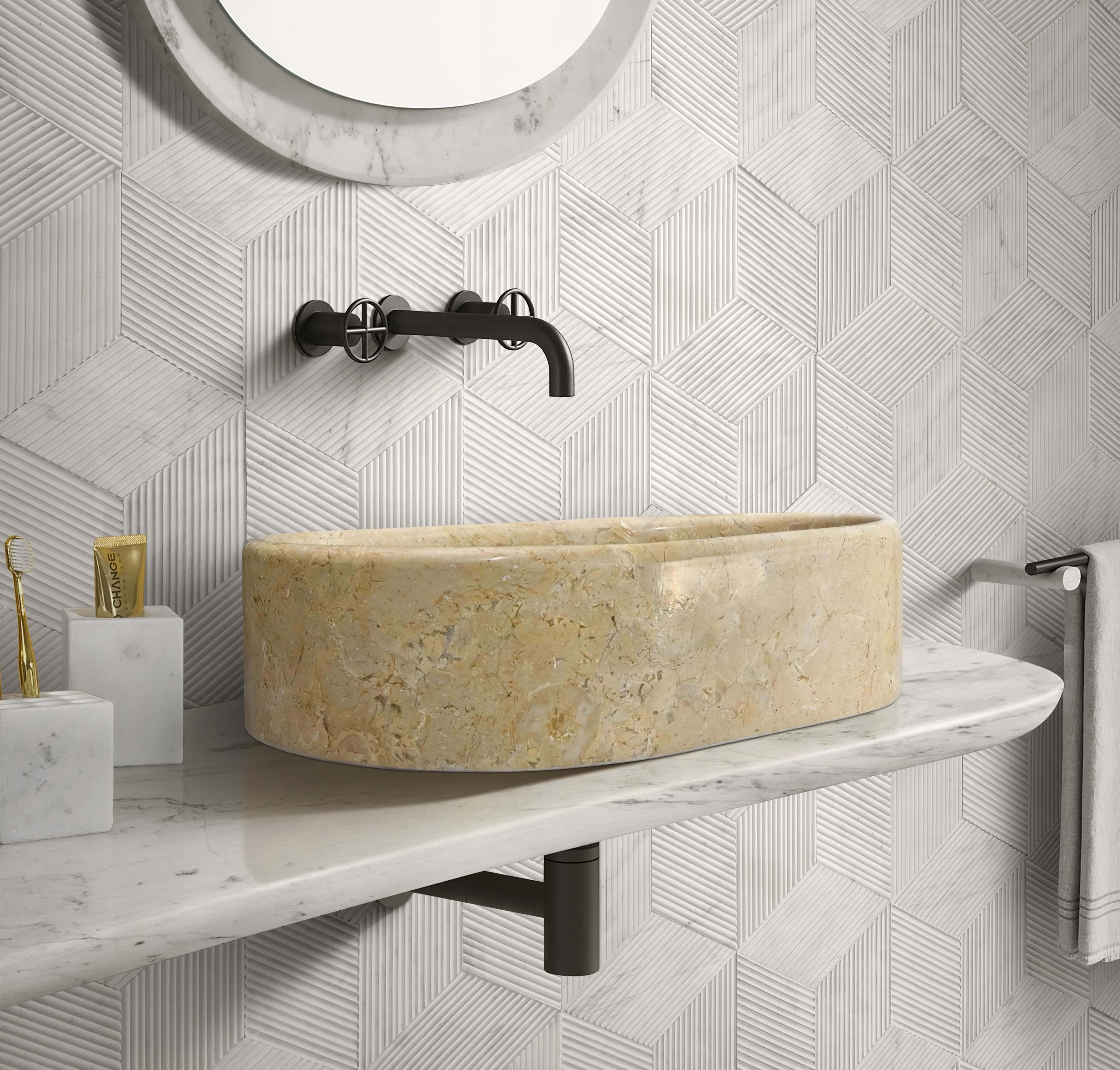 Hyatt Gold marble vessel sink with Snow Mountain White hexagon textured wall tile and two matching honed marble accessories on a marble shelf.