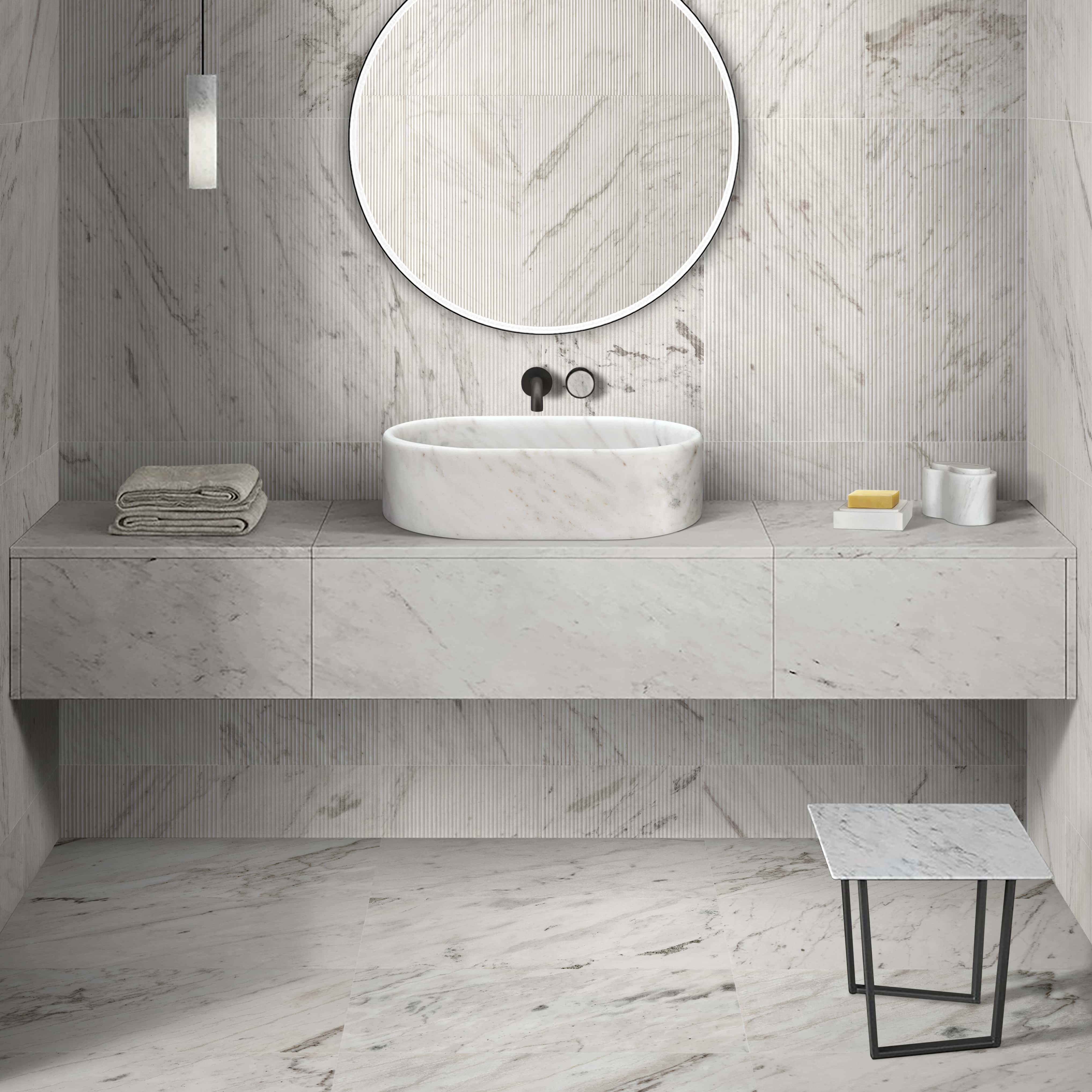 Snow Mountain White marble oval vessel sink paired with 12x24 textured wall tile, polished floor tile and matching honed marble accessories in a full bathroom suite.