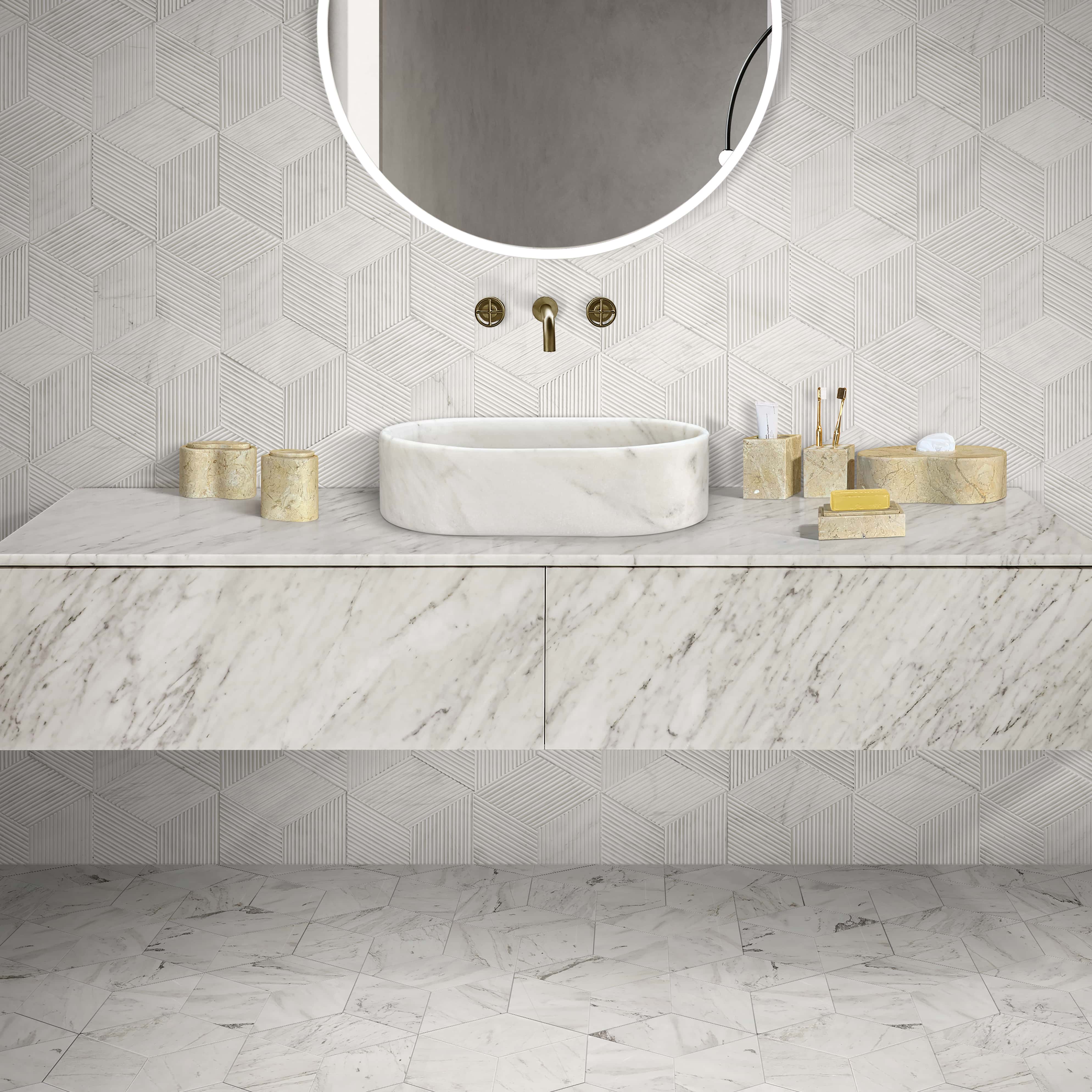 Snow Mountain White marble oval vessel sink with hexagon textured wall tile, polished hexagon floor tile and Hyatt Gold marble accessories in a coordinated bathroom.