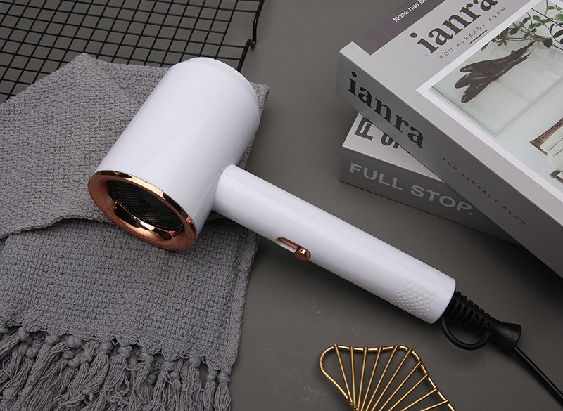 White hair dryer with rose-gold honeycomb grille resting on grey blanket