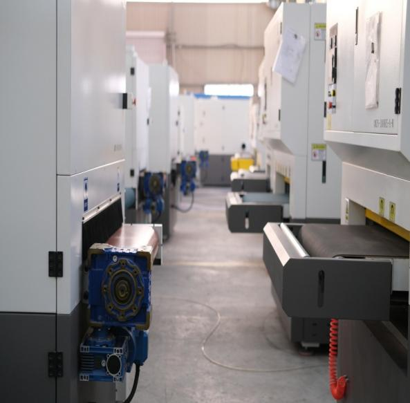 Machine conveyors and drive components facing a workshop aisle.