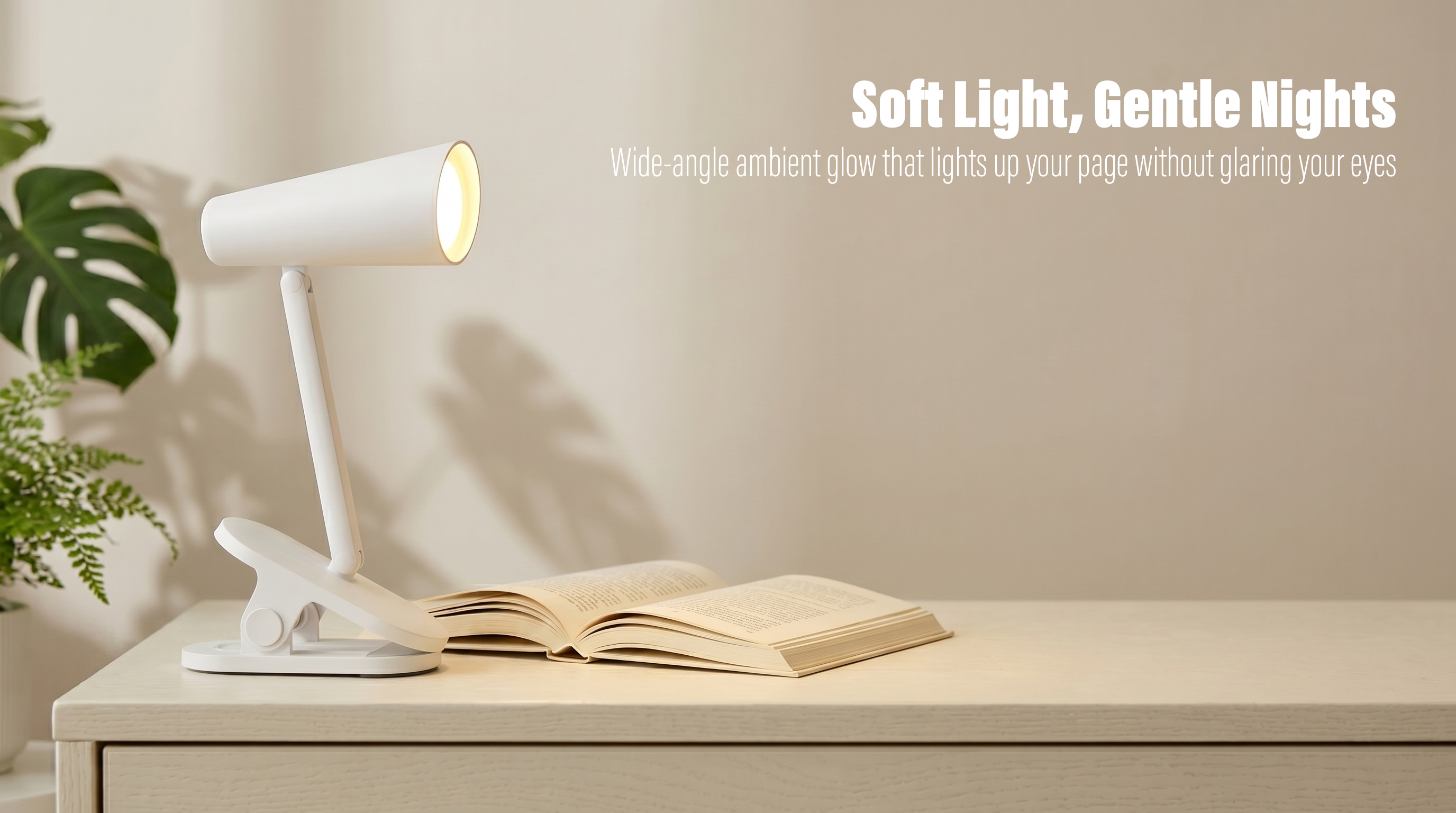 A white minimalist clip-on desk lamp with an adjustable folding arm illuminating an open book on a light wooden table next to a green plant