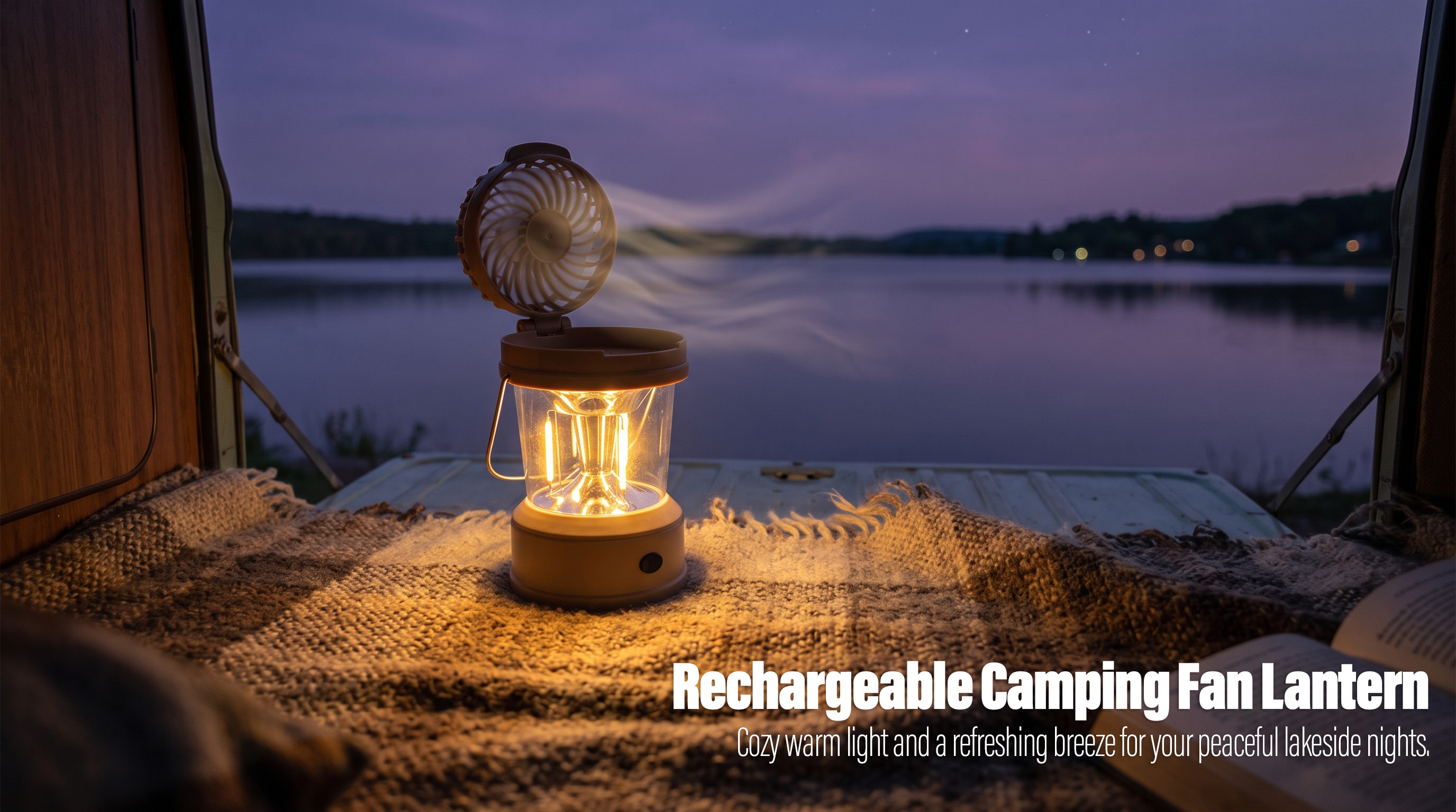 A rechargeable camping fan lantern with glowing warm light and an active top fan sitting on a blanket inside a camper van trunk facing a lakeside sunset.