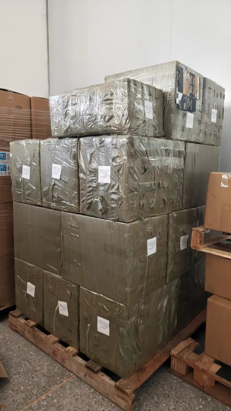 Stacked and wrapped cardboard boxes on a wooden pallet in a warehouse.