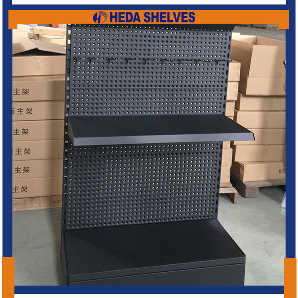 Original HEDA PBDS01 factory front photograph showing black round-hole pegboard panels, horizontal panel joints, black projecting mid-level merchandise shelf, side uprights and lower display platform