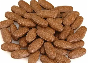 Brown oval polished tablets produced by a tablet polishing machine