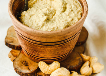 Creamy cashew butter in a wooden bowl, smooth texture with whole cashews