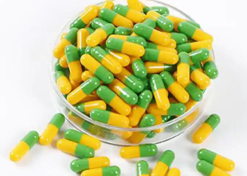 Green-yellow two-color empty hard capsules in glass dish