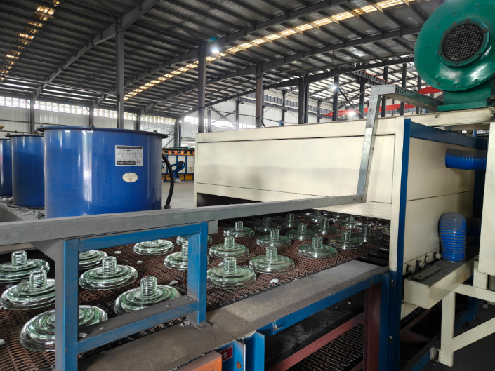 Workers handling glass suspension insulators on a production line