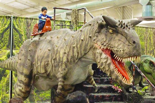 Paseo en dinosaurio para niños en el parque de atracciones