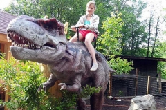 Paseo en dinosaurio para niños en el parque de atracciones