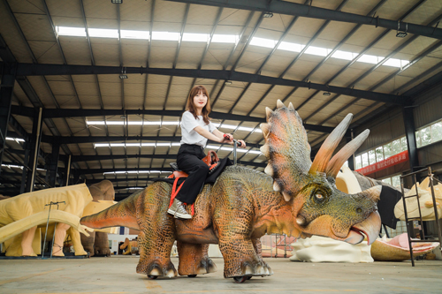 Paseo en dinosaurio animatrónico que funciona con monedas en el parque temático