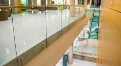Standoff glass railing with stainless steel handrail for commercial