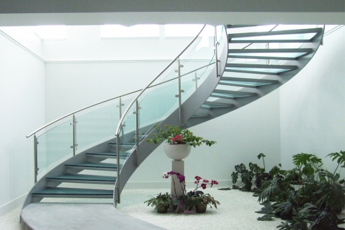 Modern commercial curved staircase with frosted glass tread and glass railing