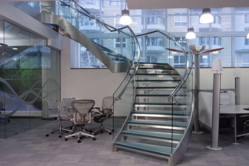 Freestanding curved glass staircase with glass railings and frosted glass stair tread