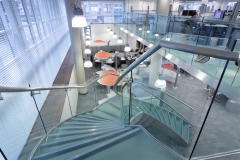 Freestanding curved glass staircase with glass railings and frosted glass stair tread