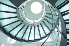 Modern commercial curved staircase with frosted glass tread and glass railing