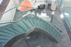 Freestanding curved glass staircase with glass railings and frosted glass stair tread