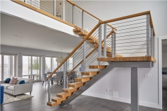 Indoor mono stringer staircase with cable railing and wood handrail