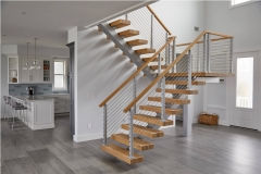 Indoor mono stringer staircase with cable railing and wood handrail