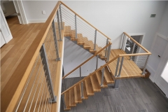 Indoor mono stringer staircase with cable railing and wood handrail