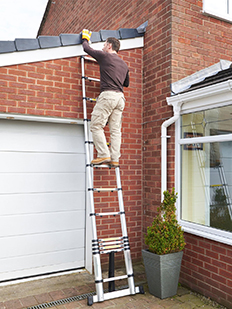 Un hombre está reparando el techo con escalera telescópica