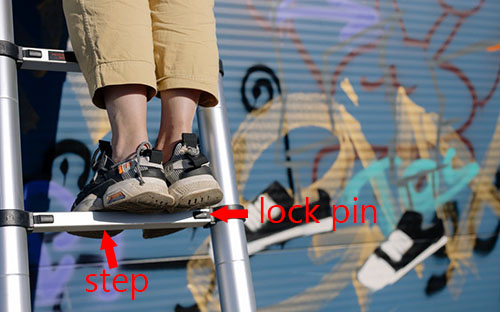 una niña de pie en una escalera telescópica, graffiti con escalera telescópica