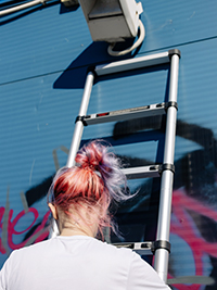 uma garota está subindo uma escada telescópica de fecho suave de 3,8 m para pintar