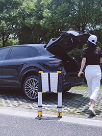 Woman prepares to put the telescopic extension ladder next to car into car trunk