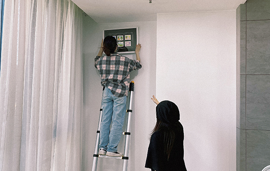 two girls are hanging a picture with a soft close telescopic ladder