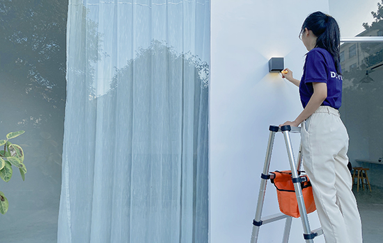 girl with a screwdriver in her hand is standing on a double side telescopic ladder