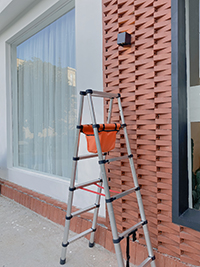 a double side telescopic ladder is in front of big window